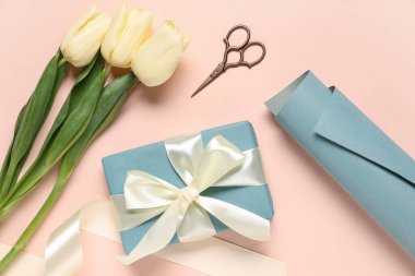 Laleli hediye kutusu, bej arka planda ambalaj kağıdı ve makas. Uluslararası Kadınlar Günü