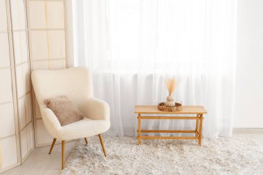 Katlanan perdeli koltuk ve odada ışık perdesinin yanındaki masa.