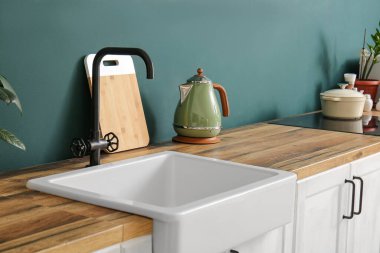 Mutfağın içinde tezgah, elektrikli su ısıtıcısı ve lavabo var. Yakın çekim.