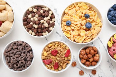 Mermer arka planda farklı mısır gevrekleri olan kaseler, yakın plan.