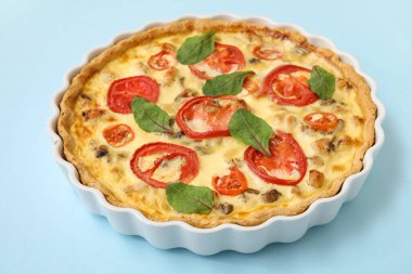 Mavi arka planda ıspanak yapraklı lezzetli domates tartı.