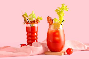 Pembe arka planda domuz pastırmalı ve kerevizli Bloody Mary kokteyli.
