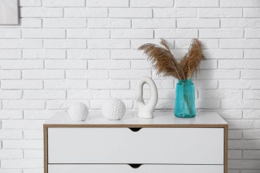 Beyaz tuğla duvarın yakınındaki çekmecelerde saksı ve dekoru olan nane vazosu.