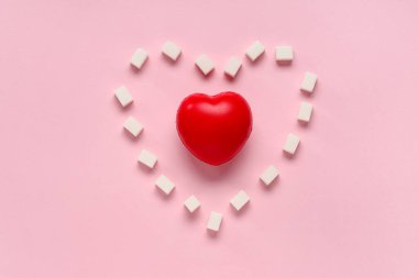 Pembe arka planda kırmızı kalpli küp şekerler.