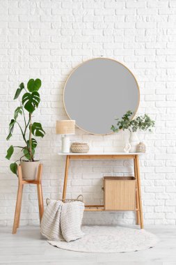 Dekorlu masa, beyaz tuğlalı duvarda ev bitkisi ve ayna.