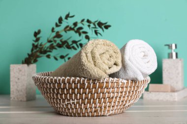 Turkuaz arka planda temiz yumuşak havlularla hasır sepetli kompozisyon, yakın plan