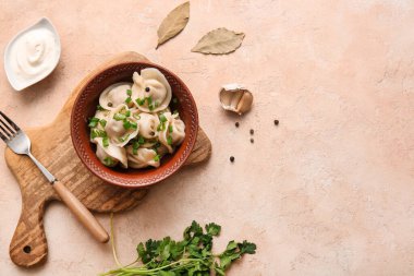 Bir kase lezzetli haşlanmış hamur köftesi, yeşil soğan ve bej arka planda ekşi krema.