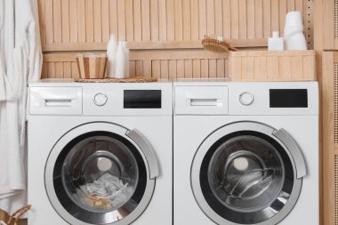 Çamaşır odasında banyo aksesuarları olan modern çamaşır makinesi, yakın plan.