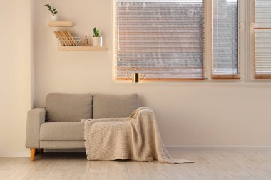 Gri kanepeli, raflı ve pencereli aydınlık oturma odasının içi.