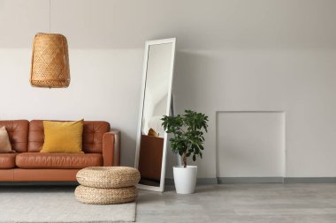 Rahat bir kanepe ve odanın içindeki beyaz duvarın yanındaki zemin aynası.