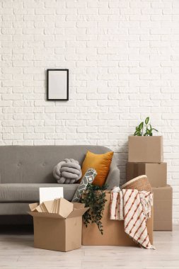Taşındığı gün beyaz tuğla duvarın yanında karton kutular olan kanepe.