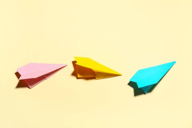 Açık sarı arkaplanda renkli kağıt uçaklar