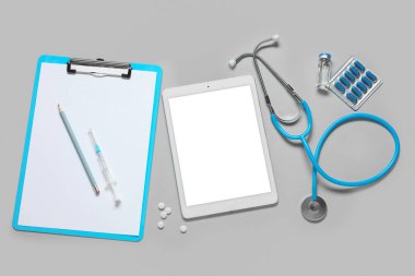 Açık arkaplanda doktor malzemeleri olan boş bir tablet bilgisayar