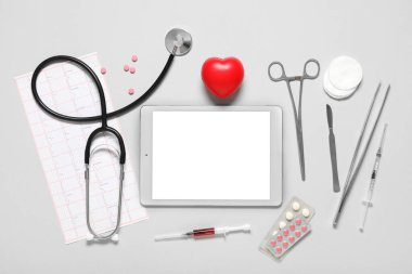 Açık arkaplanda kalp ve doktor malzemeleri olan boş bir tablet bilgisayar