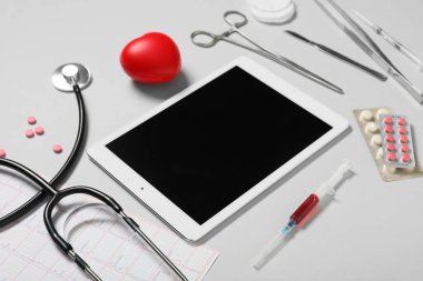 Açık arkaplanda kalp ve doktor malzemeleri olan boş bir tablet bilgisayar