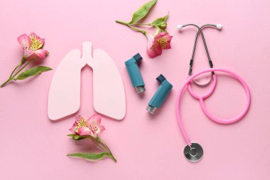 Steteskoplu astım spreyleri, kağıt ciğerler ve pembe arka planda alstromerya çiçekleri.