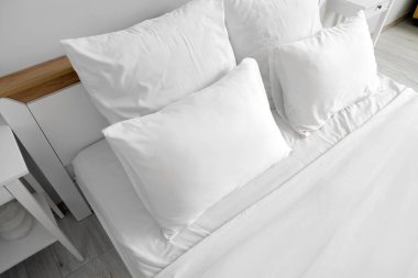 Odasında beyaz çarşaf olan büyük yatak.