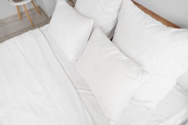 Odasında beyaz çarşaf olan büyük bir yatak, üst manzara.