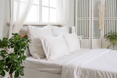 Beyaz çarşaflı ve katlanır perdeli bir odanın içinde.