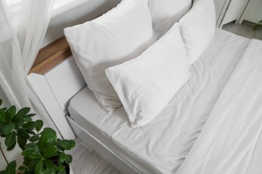 Odasında beyaz çarşaf olan rahat yatak.