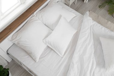 Odasında beyaz çarşaf olan rahat bir yatak, üst manzara.