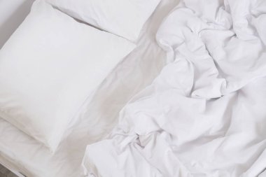 Odasında beyaz çarşaf olan büyük bir yatak, üst manzara.