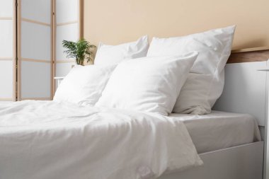 Odasında beyaz çarşaf olan büyük yatak.