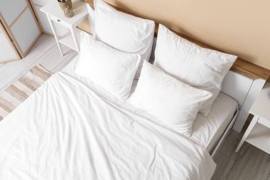 Odasında beyaz çarşaf olan büyük bir yatak, üst manzara.