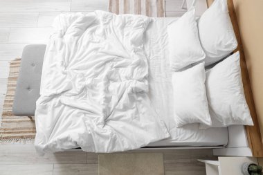 Odasında beyaz çarşaf olan büyük bir yatak, üst manzara.