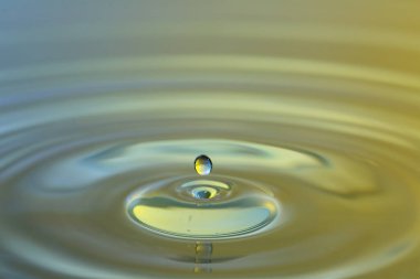 Renkli arkaplanda sıçrama olan su damlasının yakın görüntüsü