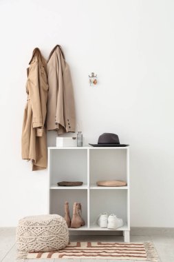 Raflar, elbiseler ve anahtarlar beyaz duvarda asılı olan şık bir salonun içinde.