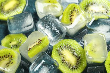 Koyu arkaplanda taze kivi olan buz küpleri, yakın plan.