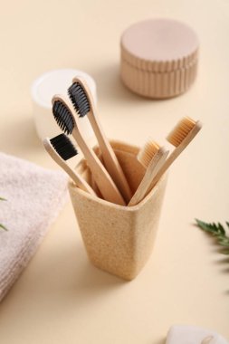 Bej arka planda ahşap diş fırçaları olan cam, yakın plan.