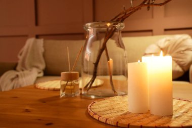 Gece şık oturma odasındaki koltuğun yanında yanan mumlar ve aroma çubukları olan kahve masası.