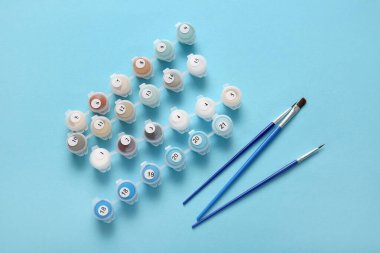 Boya ve fırçaları mavi arkaplandaki numaralara göre boyar