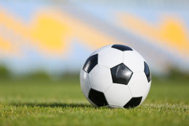 Yeşil stadyum çimlerinde futbol topu, yakın plan.