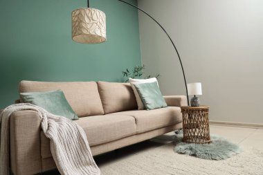 Gri kanepesi, masası ve lambası olan şık bir oturma odası.