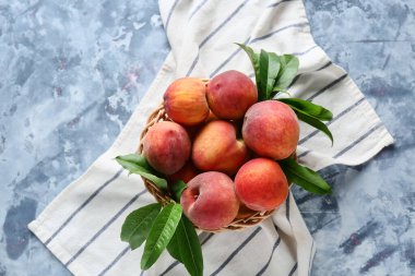 Mavi arka planda bir sepet taze şeftali.