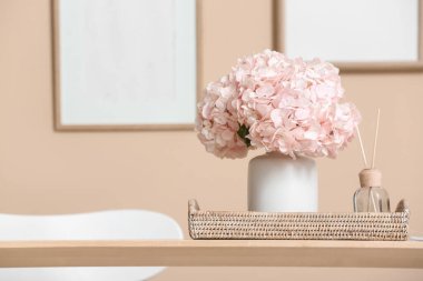 Yemek masasında pembe ortanca çiçekli tepsi ve sazlık ayırıcı, yakın plan.