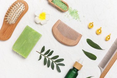 Saç fırçası, tarak, vitamin kapsülleri ve beyaz grunge arka planda bir şişe kozmetik ürünü içeren kompozisyon, yakın plan