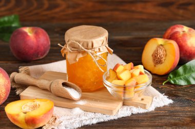 Reçel kavanozu, taze şeftali ve ahşap arka planda bir top şeker.