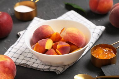 Dilimlenmiş şeftali kasesi, ölçü kabı şeker ve reçel gri grunge arka planda