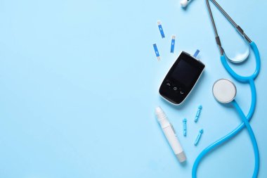 Glukometre, tükenmez kalem, steteskop ve mavi arka planda test şeritleri. Diyabet kavramı