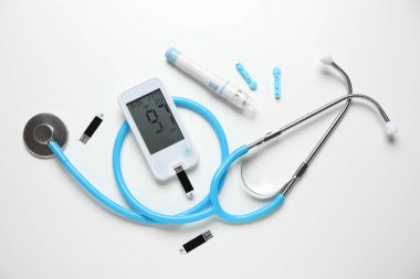 Glukometre, tükenmez kalem, steteskop ve beyaz arka planda test şeritleri. Diyabet kavramı