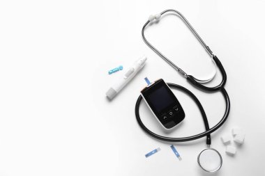 Glukometre, tükenmez kalem, steteskop, şeker ve beyaz arka planda test şeritleri. Diyabet kavramı
