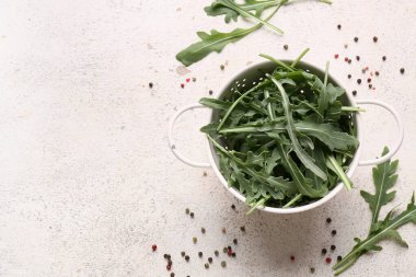 Beyaz arka planda taze roka yaprakları ve biberli Colander.