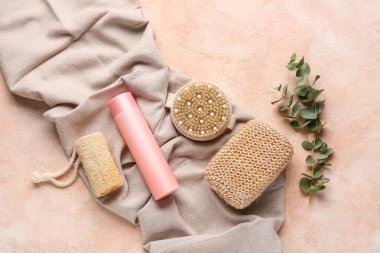 Kumaş, masaj vücut fırçası, süngerler ve pembe grunge arka planda bir şişe kozmetik ürünle kompozisyon