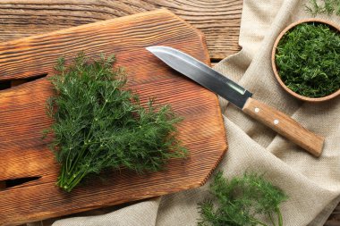 Tahta arka planda taze yeşil dereotlu kase ve kesim tahtası