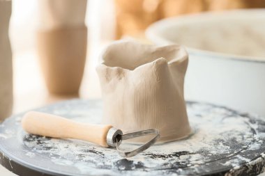 Ev stüdyosundaki çömlek çarkında kil kap ve döngü aracı, yakın plan.