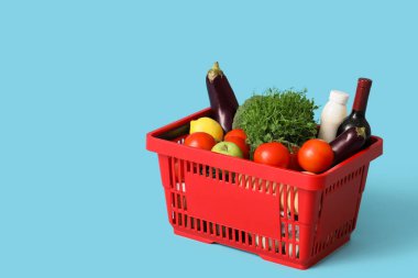 Kırmızı alışveriş sepeti ve mavi arka planda farklı taze ürünler.